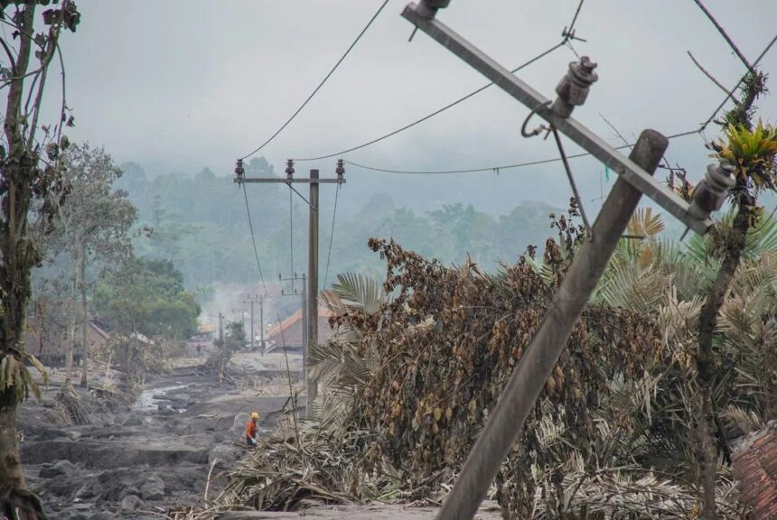 Petugas melintas di dekat tiang penyulang listrik yang rusak akibat terdampak erupsi Gunung Semeru di Desa Supiturang, Pronojiwo, Lumajang/ Foto: courtesy ANTARA