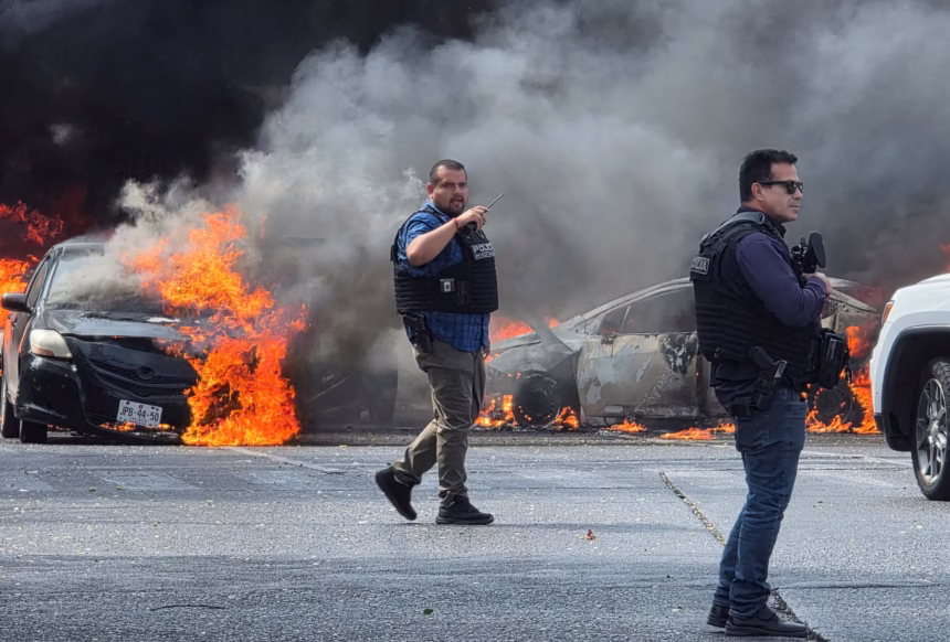Polisi Meksiko tiba di lokasi kejadian di mana kendaraan-kendaraan dibakar oleh geng kriminal untuk memblokir jalan di Zapopan menyusul pembunuhan gembong narkoba Nemesio Oseguera/ Foto: The Guardian