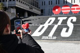 Seorang turis asing mengambil foto instalasi jalanan yang mempromosikan BTS di Lapangan Gwanghwamun di pusat Seoul/ Foto: Korean Times