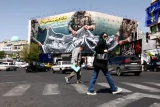 Warga Teheran melewati poster menentang AS/ Foto: the guardian