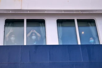 Para penumpang menyaksikan penumpang lain turun dari kapal pesiar MV Hondius yang terjangkit virus hantavirus di pelabuhan Granadilla di Tenerife, Kepulauan Canary, Spanyol/ Foto: APNews