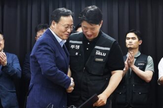 Choi Seung-ho (kanan), kepala serikat pekerja terbesar Samsung Electronics Co., berjabat tangan dengan Yeo Myeong-gu (kiri), kepala tim SDM divisi solusi perangkat Samsung Electronics Co.,/ Foto: Yonhap