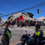 Polisi berkumpul di depan reruntuhan restoran cepat saji Jollibee setelah gempa bumi di Kota General Santos, Filipina/ Foto: capture The Guardian