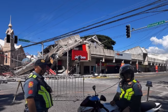 Polisi berkumpul di depan reruntuhan restoran cepat saji Jollibee setelah gempa bumi di Kota General Santos, Filipina/ Foto: capture The Guardian